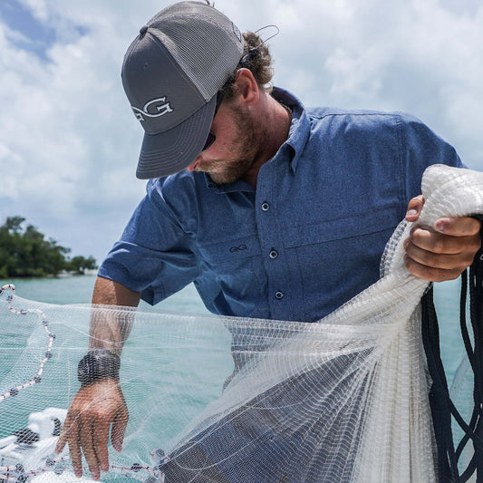 Man holding a fishing net by a body of water